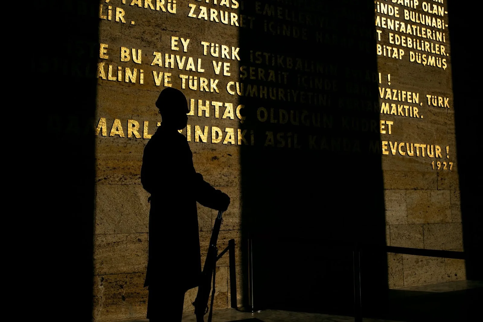Silhouette of a soldier holding a rifle, displayed against a wall with historical inscriptions in Ankara, Türkiye.