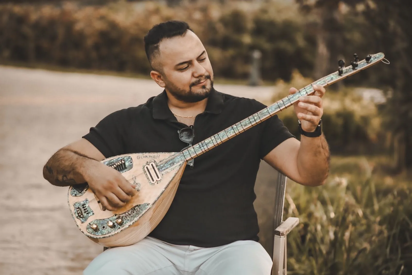 A man plays a Turkish Baglama in an outdoor setting, creating a serene musical atmosphere.