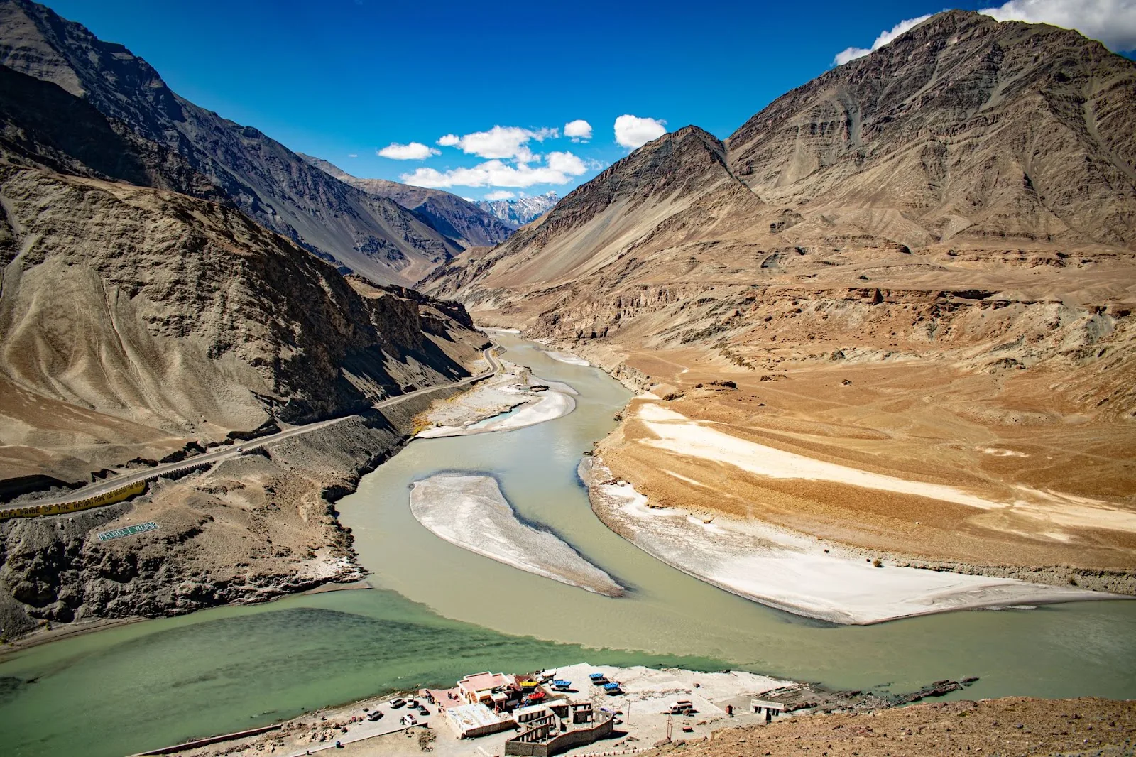 A breathtaking view of the Indus and Zanskar rivers converging surrounded by majestic Ladakh mountains.