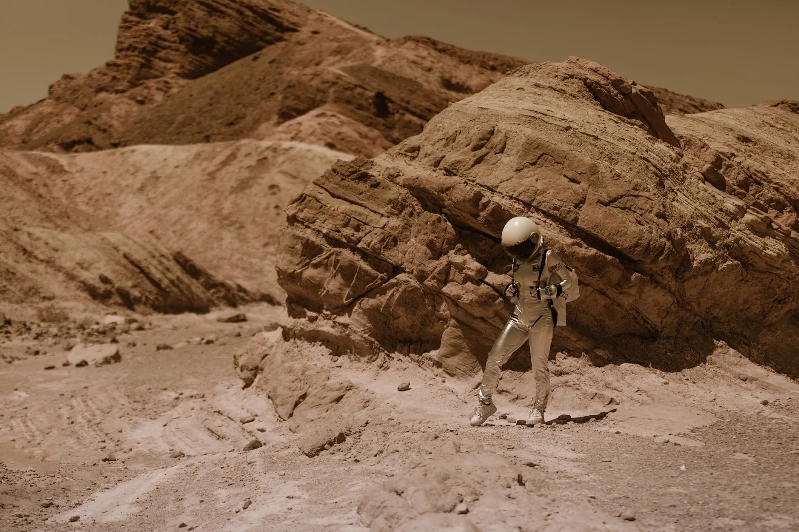 An astronaut in a space suit explores a barren desert landscape, resembling an alien planet.