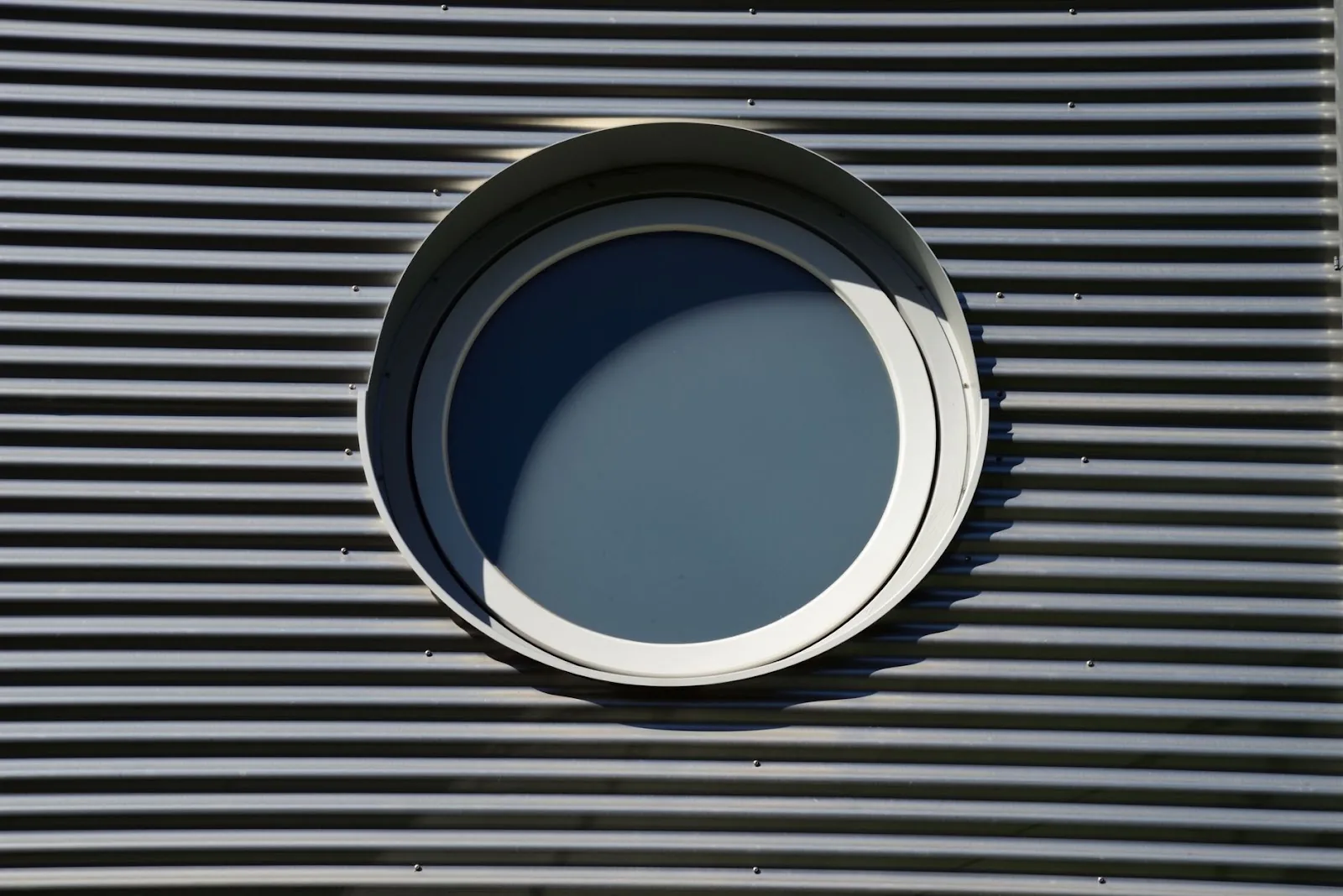 A round window in a metal facade, showcasing architectural design in Freiburg im Breisgau.