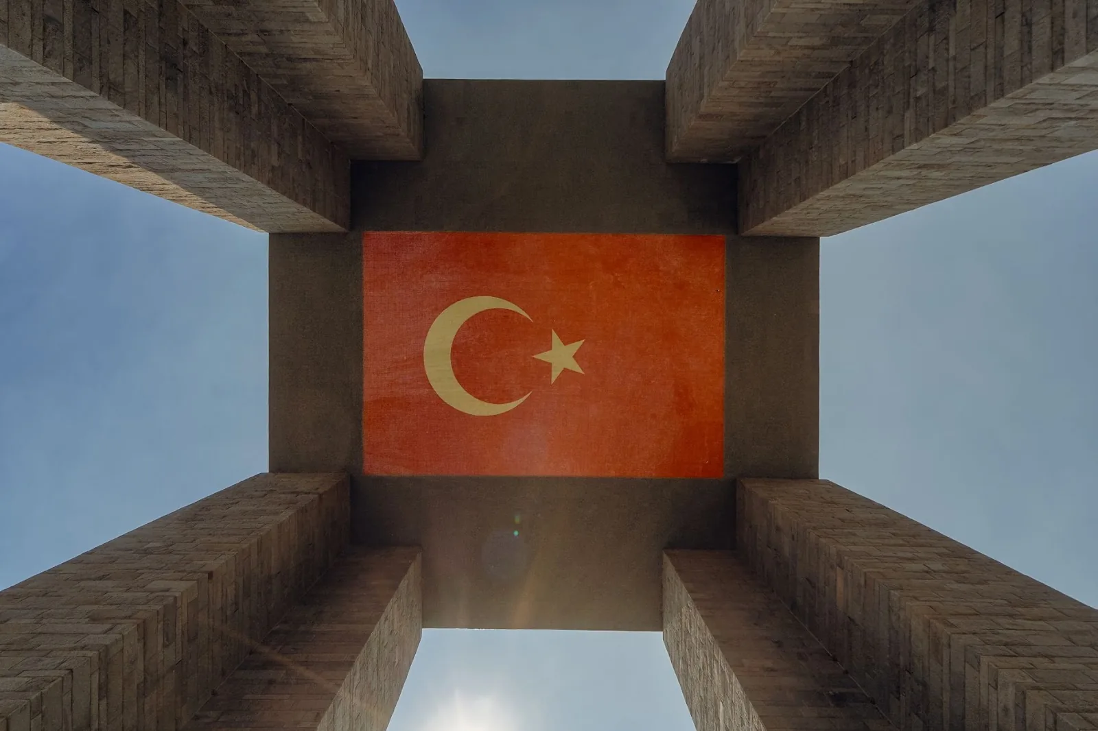 Upward view of the Çanakkale Martyrs' Memorial featuring the Turkish flag against the sky.